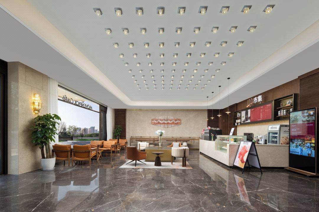 Um saguão de hotel com balcão de recepção, área de estar e uma grande janela com vista para a cidade.