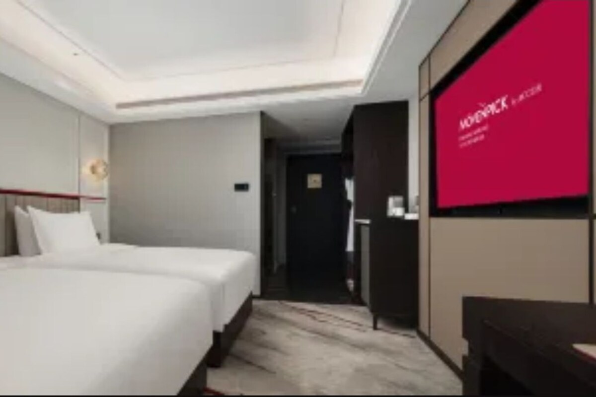 A hotel room with two beds, a large mirror, and a red wall.