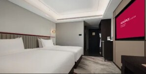 Habitación de hotel con dos camas, un espejo grande y una pared roja.