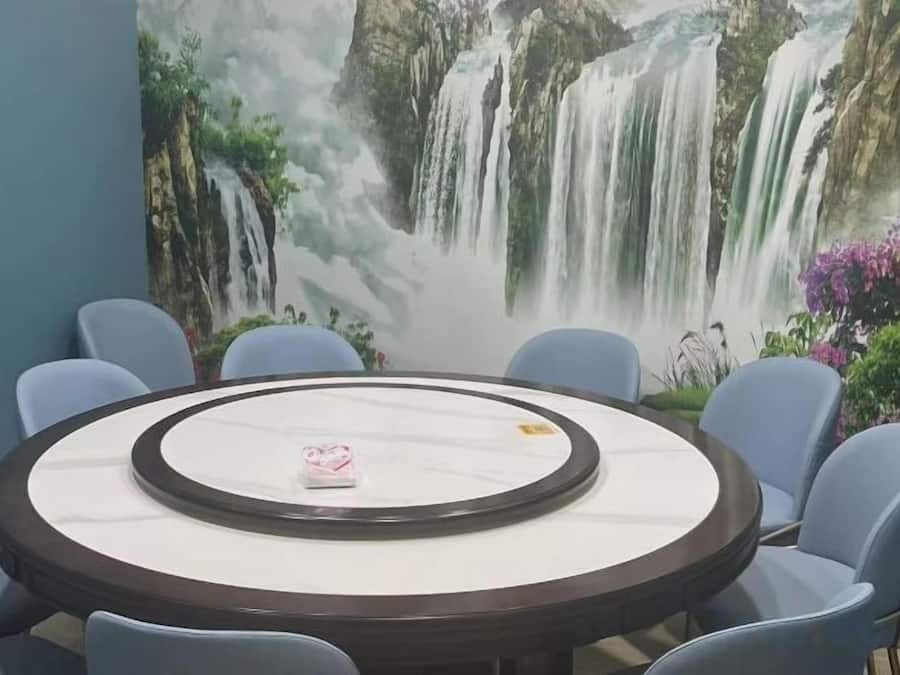 A round table with a marble top surrounded by chairs, set against a wall with a waterfall mural.