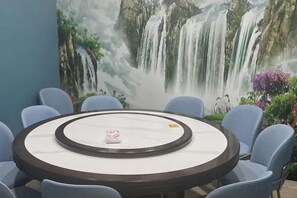 A round table with a marble top surrounded by chairs, set against a wall with a waterfall mural. - GreenTree Inn Express Hotel (Beijing)