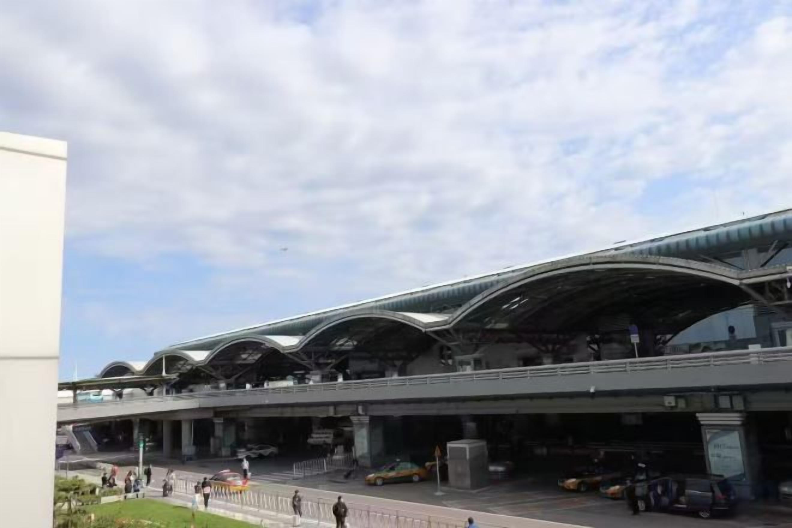 A modern building with a curved roof and a covered pedestrian walkway.