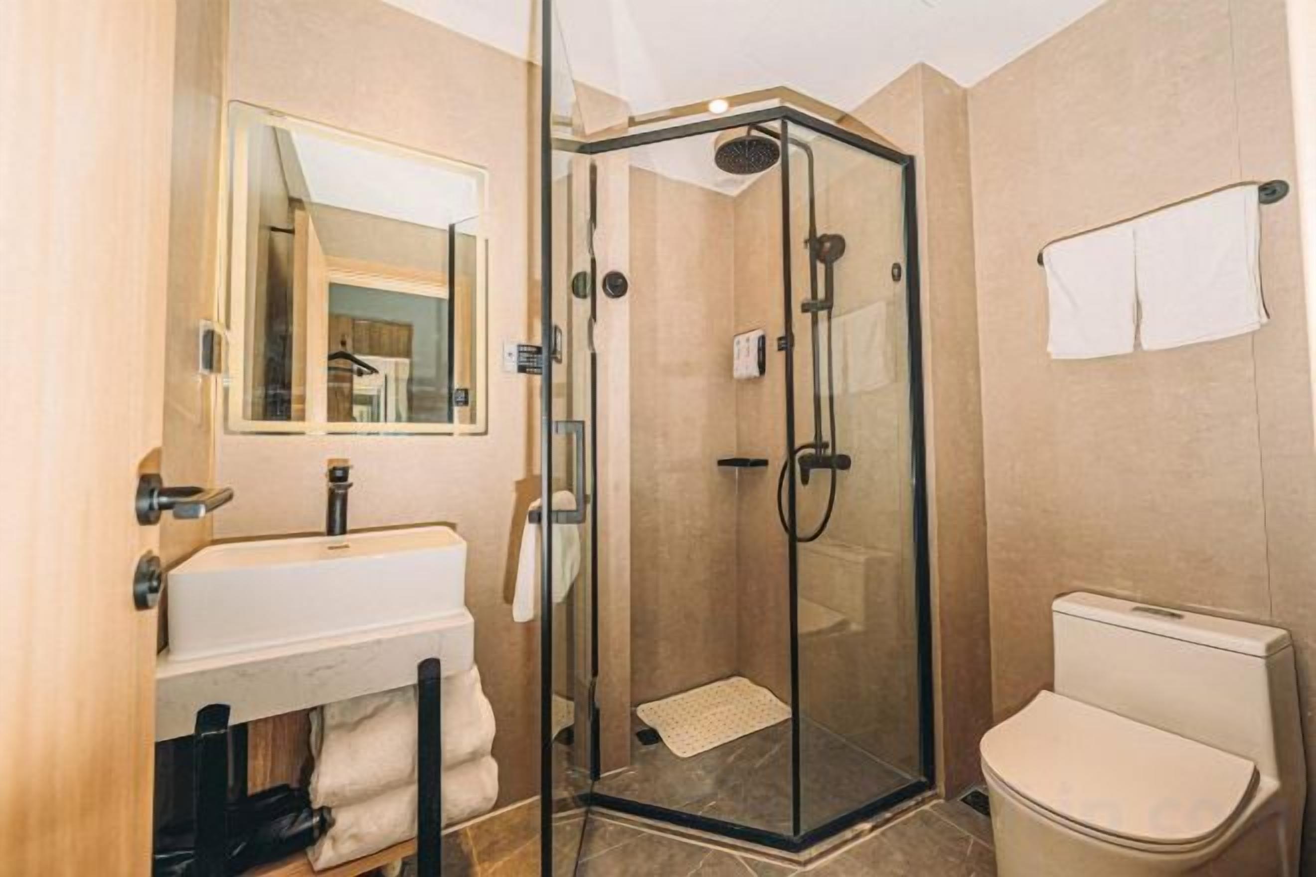A bathroom with a glass-enclosed shower, a sink, and a toilet.