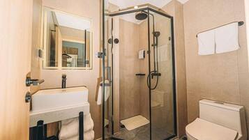 A bathroom with a glass-enclosed shower, a sink, and a toilet.