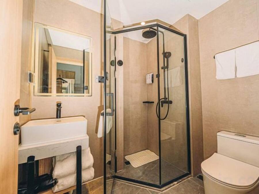 A bathroom with a glass-enclosed shower, a sink, and a toilet.