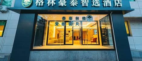A hotel entrance with a modern design, featuring a glass facade and a welcoming interior.