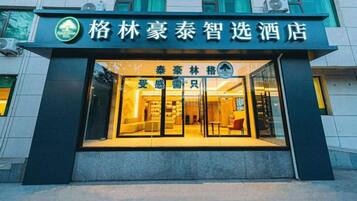 A hotel entrance with a glass facade, signage, and a visible interior with seating.