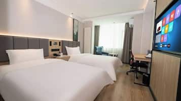 A hotel room with two beds, a desk, a chair, and a large screen displaying apps.