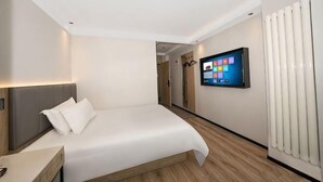 A modern hotel room with a bed, bedside table, and a mounted TV displaying a digital interface. - GreenTree Inn Express Hotel (Beijing)