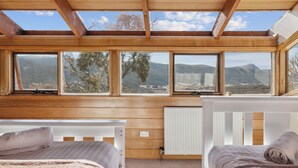 A bedroom with wooden walls, a skylight, and a view of mountains. - Nowhere Apartment Crackenback (Crackenback)