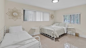 A bedroom with two beds, a small table, and decorative wall art.