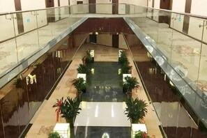 Een meerlaags atrium met glazen balustrades, een glanzende vloer en potplanten.