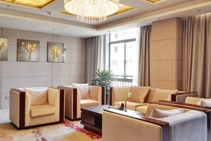 A modern living room with sofas, a coffee table, and artwork on the walls. - Ziyun Dongzimen Hotel (Ziyun)