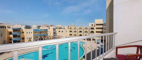 A pool area with a clear view of the surrounding buildings and a balcony with a table and chairs.