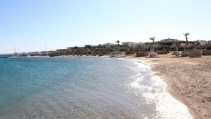 A beach with clear water, a sandy shore, and buildings in the background. - Saint Maria Hotel Hurghada (Hurghada)