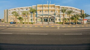 A multi-story hotel with a curved facade, palm trees, and a clear blue sky. - Saint Maria Hotel Hurghada (Hurghada)