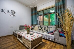 A living room with a sofa, a coffee table with a vase, and a window with curtains. - Anjiyingjun (Anji)
