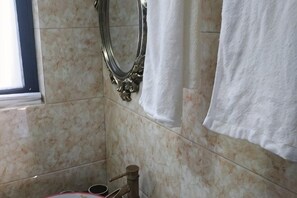 Ein Badezimmer mit Marmorwand, einem Spiegel und einem an der Wand hängenden Handtuch.