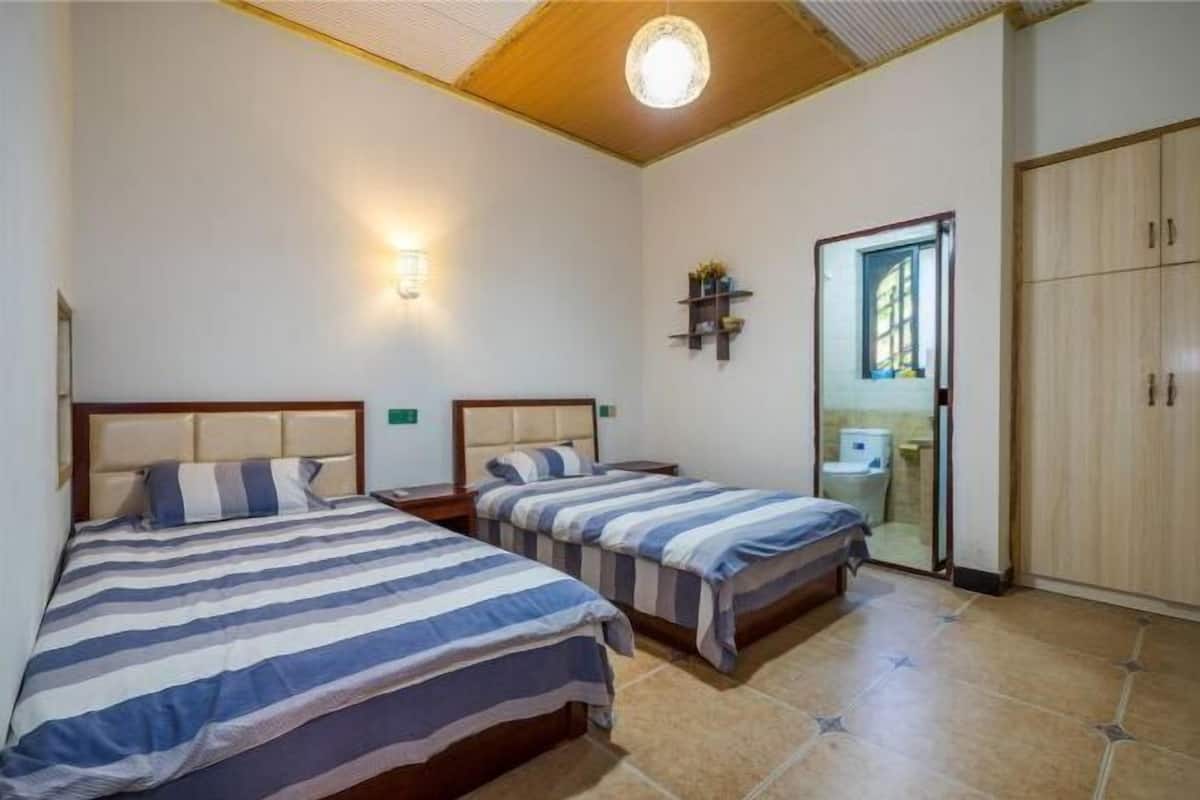 A bedroom with two beds, a nightstand, a wall-mounted shelf, a mirror, and a wardrobe.