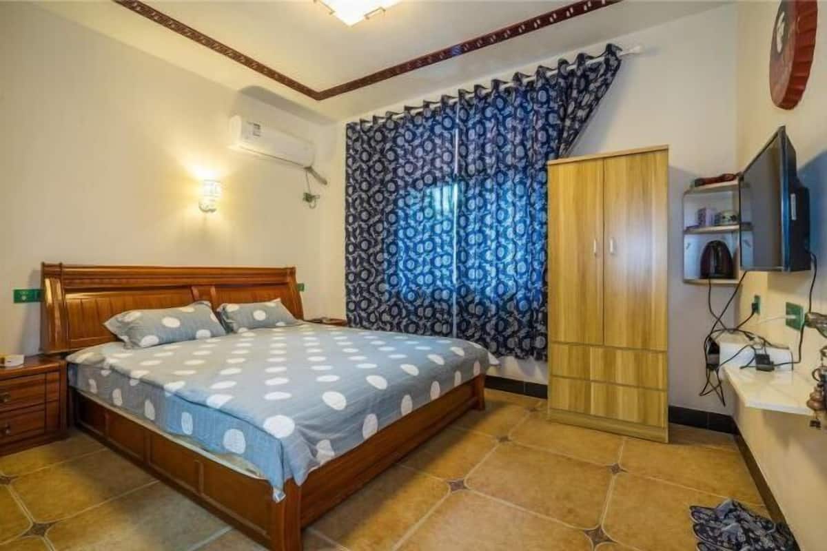 A bedroom with a wooden bed, a wardrobe, a television, and a curtain.