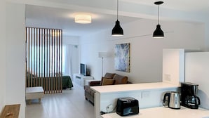 Ein moderner, gut beleuchteter Wohnbereich mit Küchenzeile, Esstisch und Sofa.