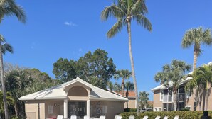 A pool area with lounge chairs and a notice sign. - 1st Floor Charming 2-bedroom condo in Bonita Springs with Community Pool (Bonita Springs)