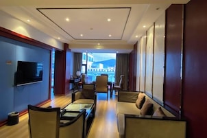 Habitación de hotel con zona de estar, televisión y vistas al exterior.