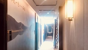 A hallway with a mural of mountains and a sign with numbers. - Shike Wangguo Hotel (Shiqu)