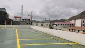 A rooftop parking area with marked parking spaces and a white wall surrounding it. - Shike Wangguo Hotel (Shiqu)