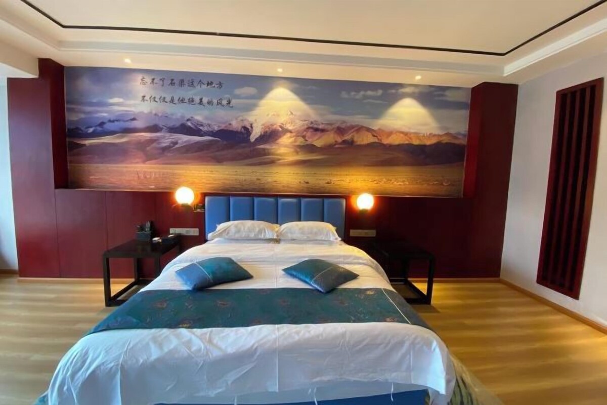 A bedroom with a large bed, two bedside tables, and a wall-mounted TV.
