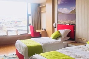 A hotel room with two beds, a desk, a chair, and a large window with a view of a cityscape. - Shike Wangguo Hotel (Shiqu)