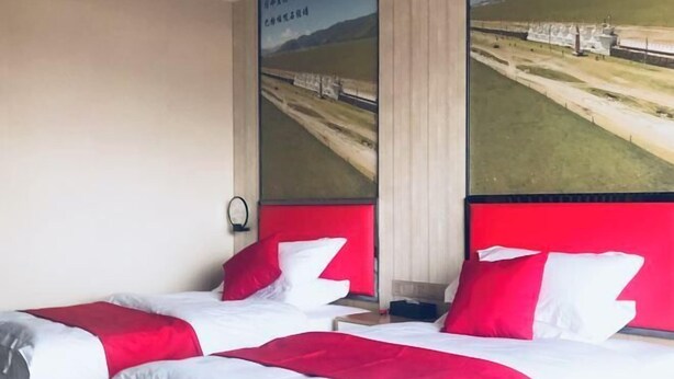 A hotel room with two beds, each with red and white bedding, and a large window with a view of a landscape. - Shike Wangguo Hotel (Shiqu)