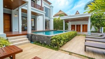 Una casa moderna con piscina, mobiliario de exterior y un patio cubierto.