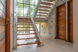 A staircase with wooden steps leading to a landing, a wooden door on the right, and a wall with a light fixture. - Villa Autjima Krabi /3Brd (Krabi)