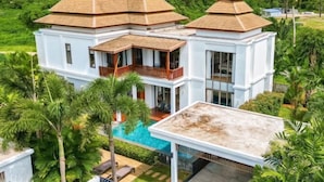 Une grande maison à deux étages, dotée d’une piscine et d’un patio couvert.