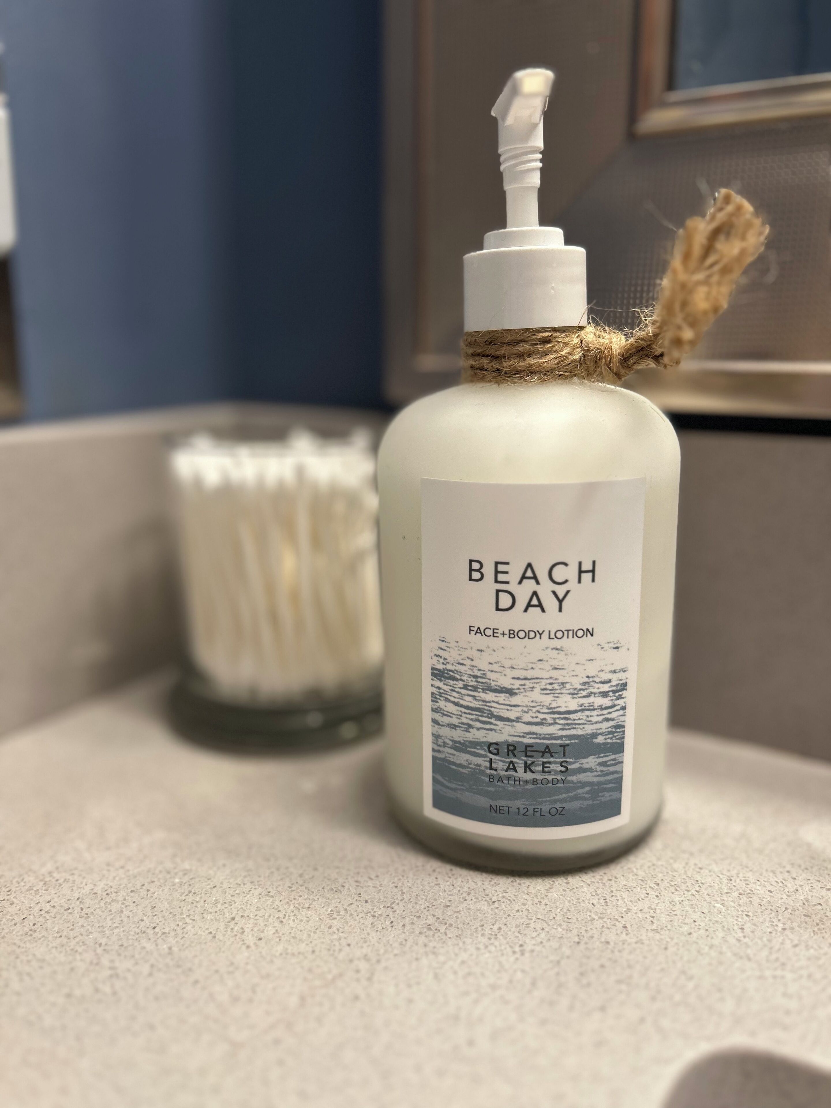 A bottle of Beach Day face and body lotion with a label featuring a beach scene, placed on a countertop.