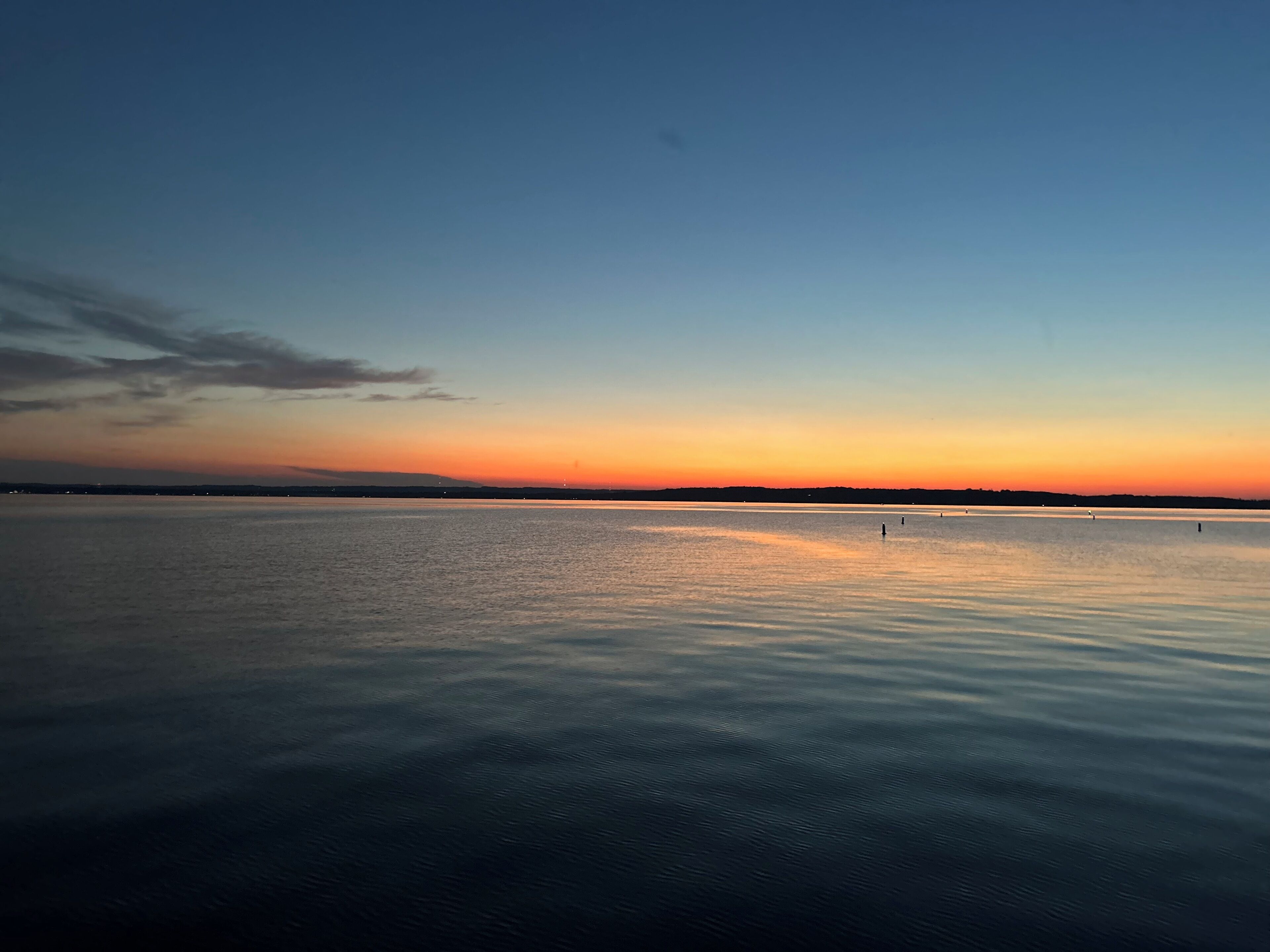 A calm body of water with a clear horizon and a gradient sky.