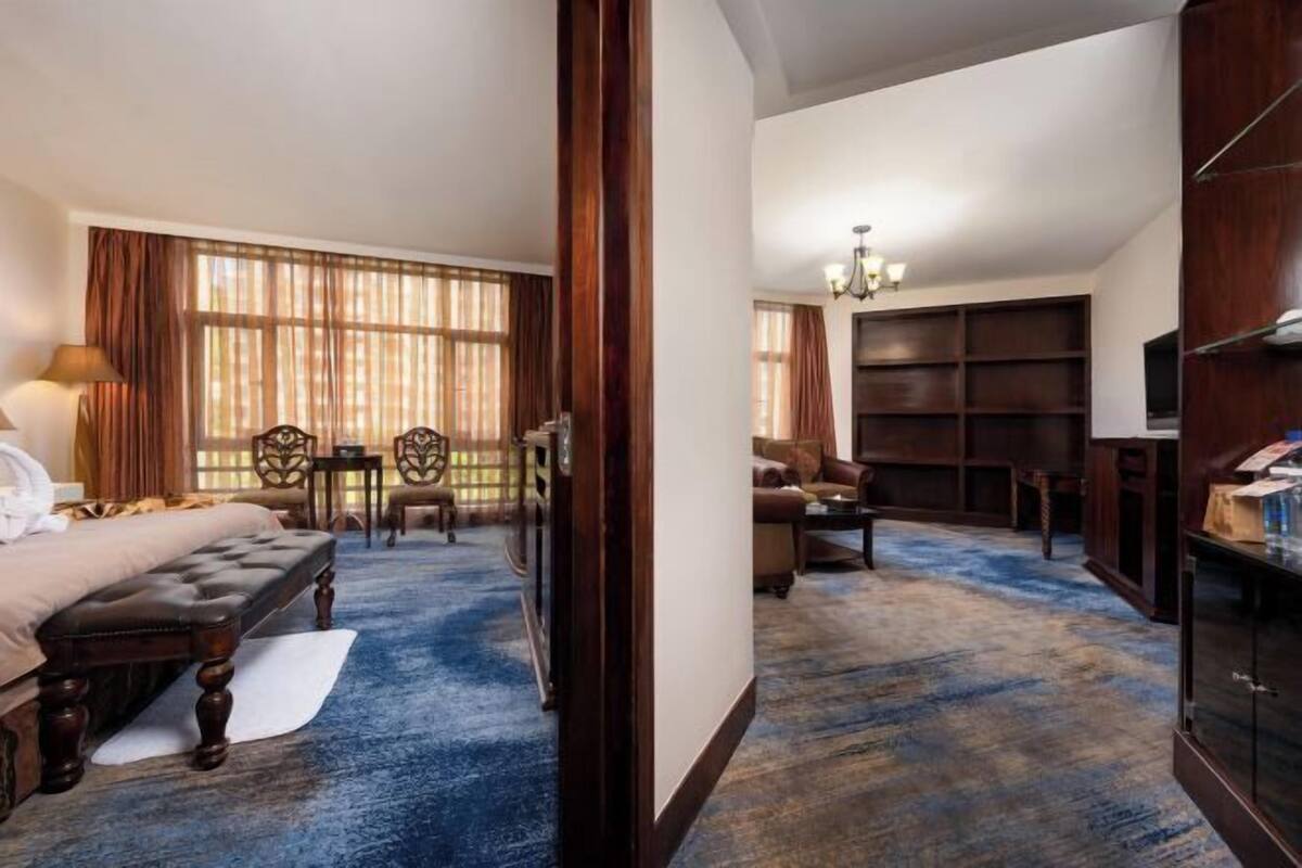 A hotel room with a bed, a desk, a chair, a sofa, and a TV.