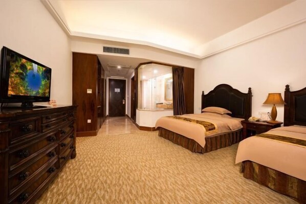 A hotel room with two beds, a TV, a dresser, and a mirror.
