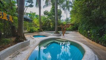 Un área de piscina con varias piscinas rodeadas de exuberante vegetación tropical.
