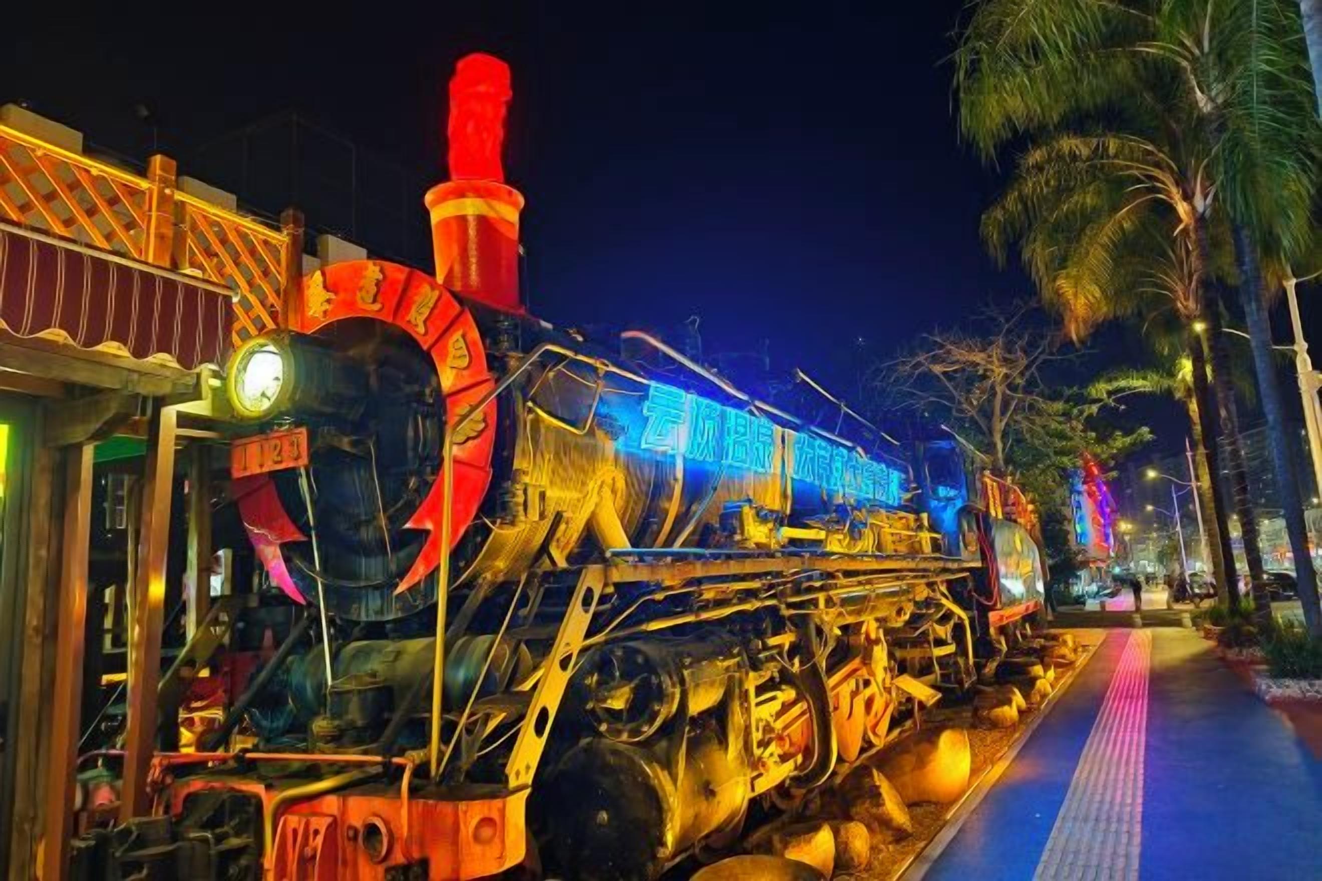 Un tren detenido con una gran parte frontal circular, una chimenea alta y un andén con un camino pavimentado accesible.