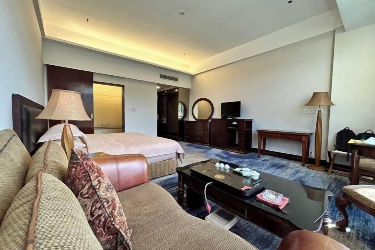 A hotel room with a bed, a sofa, a desk, a television, and a lamp.