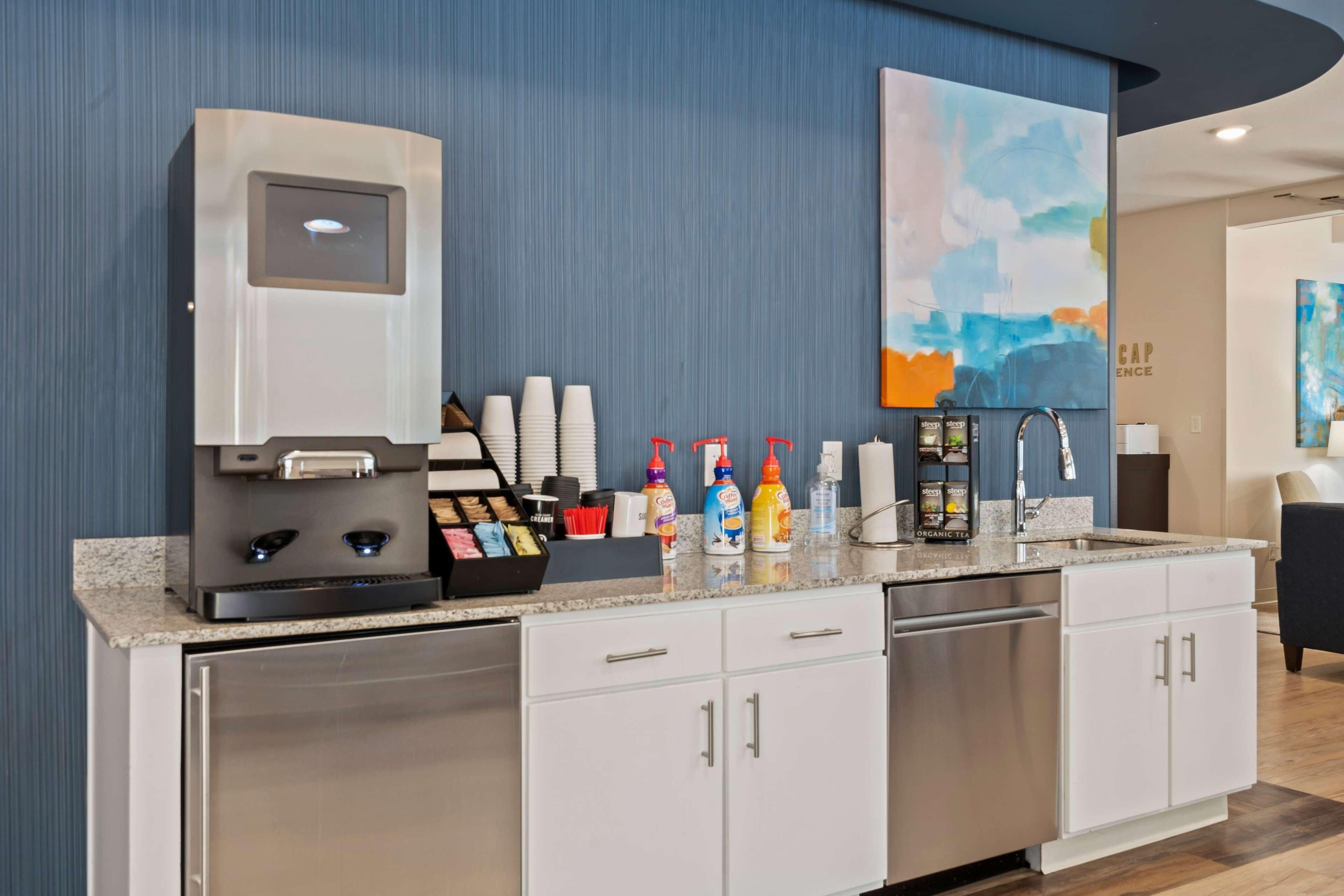 Una cocina moderna con cafetera, estación de té y diferentes condimentos.