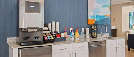 Una cocina moderna con cafetera, estación de té y diferentes condimentos.