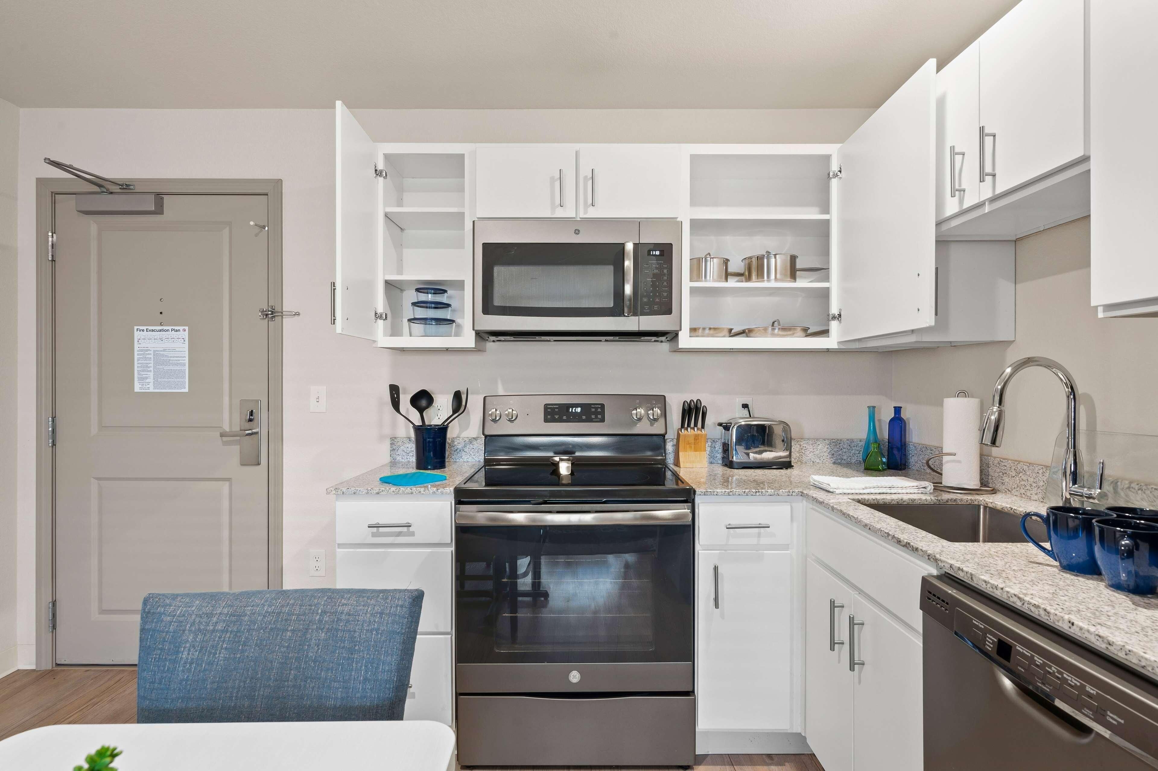 A modern kitchen with white cabinets, a stainless steel stove, a microwave, and a dishwasher.