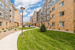 A residential building with multiple floors, a central courtyard with a lawn, and outdoor barbecue grills. - Waterwalk Extended Stay Kansas City - Overland Pk (Overland Park)