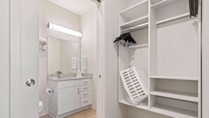 Un bagno moderno con WC, lavandino, specchio e scaffali contenitori.