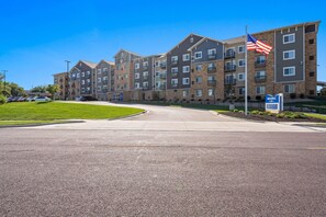 Ein mehrstöckiges Hotel mit Ziegelaußenwand, einer Fahnenstange mit der US-amerikanischen Flagge und einem Parkplatz.