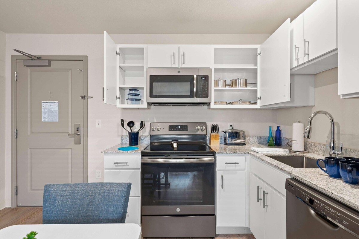 A modern kitchen with white cabinets, a stainless steel stove, a microwave, and a dishwasher.