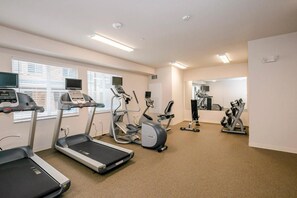 Een fitnessruimte met loopbanden, elliptische trainers en gewichttoestellen.